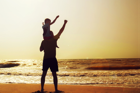 Father and son playing on the beach at the sunset time. Concept of friendly familyの写真素材