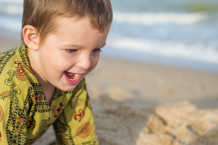 Happy laughing kid on sand beachの写真素材