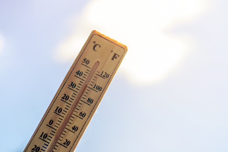 Thermometer shows high temperature against the blue skyの写真素材