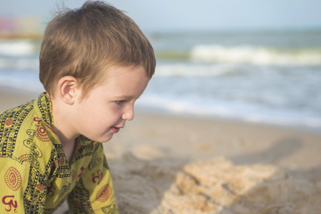 Kid playing on the beach. Cute little boy play with sand on beachの写真素材
