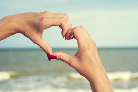 Woman making heart shape on the beachの写真素材