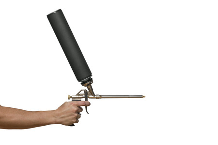 Worker hand holding polyurethane expanding foam glue gun applicator. Hand Spray foam gun worker hand isolated white backgroundの写真素材