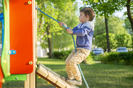 Funny cute happy baby playing on the playground. The emotion of happiness, fun, joy. Active little boy playing on playgroundの写真素材