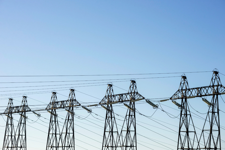 Group of posts with wires of high voltage on background of blue sky. Background image of pillars and wires in sky with copy spaceの写真素材
