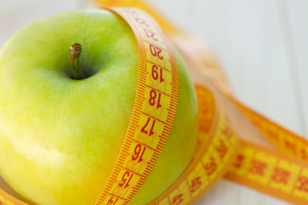 Dieting concept. Green apple with measuring tape. Green apples measured the meter, sports appleの写真素材