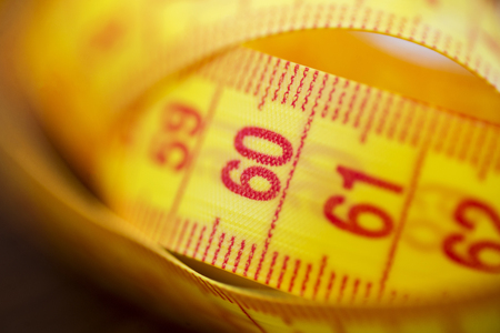 Various tape measure as background. A yellow measuring tape as background. Measuring tape of yellow color for measurement of length and volumeの写真素材