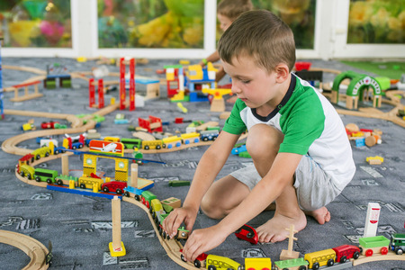 Little child playing with wooden railway on the floor. Little boy playing with wooden train setの写真素材
