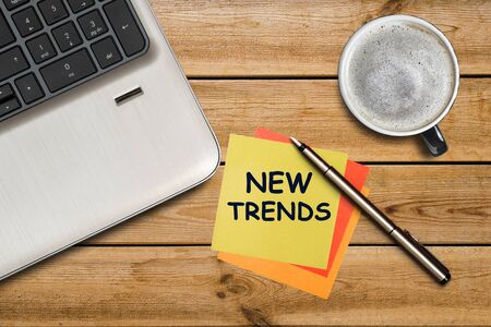 New trends written on a yellow sticker lying on a wooden table. New Trends of business concept for new yearの写真素材