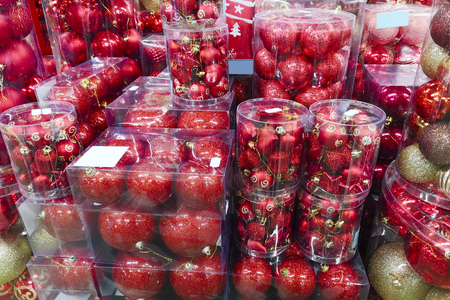 Sale of Christmas toys in the supermarket. Balls of red colors for the Christmas tree on the supermarket shelves. Christmas toys for sale in the store. Variety of red glass ballsの写真素材