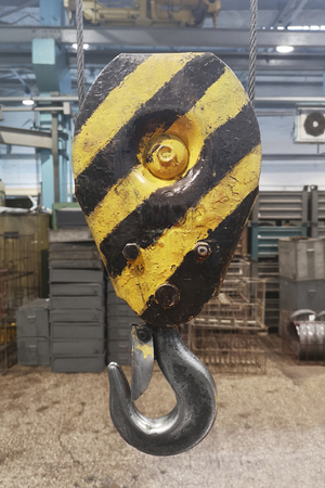 Metallic industrial hook for lifting heavy thing in the factory. Industrial yellow crane hook. Heavy duty crane hook of an old factoryの写真素材