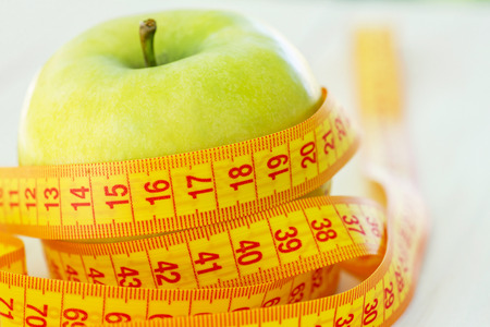 Dieting concept. Green apple with measuring tape.の写真素材