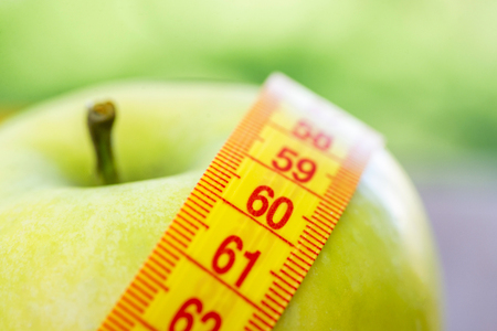Dieting concept. Green apple with measuring tape.の写真素材
