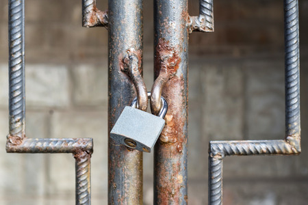 Locked lock old rusty metal door close up. Antique slide steel locked shutter door. The lock, on the grating, closedの写真素材