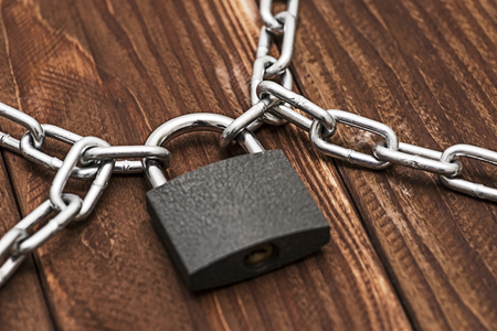Padlock and chain on wooden. Metal chain and locked padlock on wooden.の写真素材