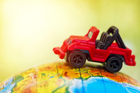 A red car on globe on green with sunshine. Miniature car toy on globe. Travel conceptの写真素材