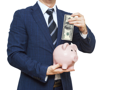 Businessman putting one hundred dollar into piggy bank. Businessman in suit is holding piggy bank. Finance Savings conceptの写真素材