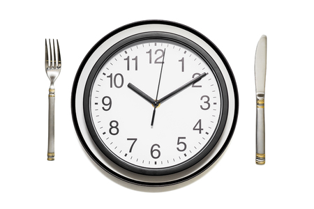 Clock dinner plate with a fork and knife on white background. Clock on plate and knife and fork on white background, top view. Lunch time conceptの写真素材