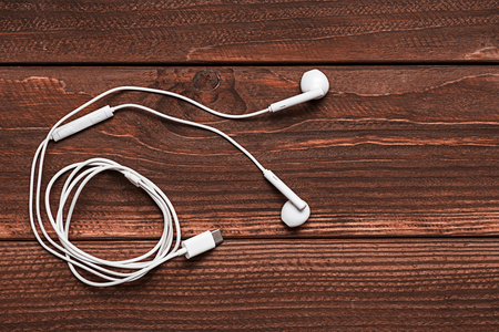 White headphones on wooden background. White earphones on wooden boards with copy space. Personal audio deviceの写真素材