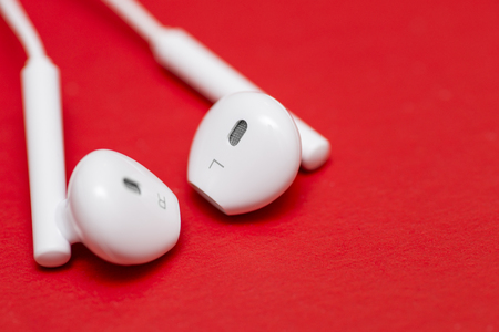 Closeup of white earphones on red background. Music is my life concept. Earphons on red background. Trendy colorful photoの写真素材