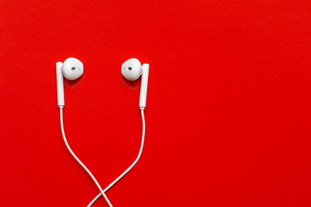 Top view of White Earphones on red background. Copy space. Music is my life concept. Minimal style with colorful paper backdropの写真素材