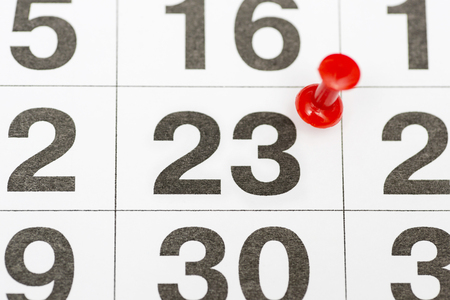 Pin on the date number 23. The twenty-third day of the month is marked with a red thumbtack. Pin on calendar. Calendar concept for important date, busy day, appointment or meeting reminderの写真素材
