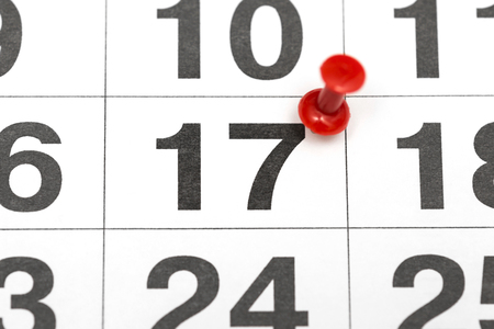 Pin on the date number 17. The seventeenth day of the month is marked with a red thumbtack. Pin on calendar. Calendar concept for important date, busy day, appointment or meeting reminderの写真素材