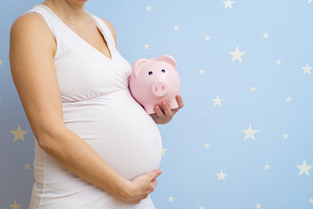 Body pregnant in underwear with moneybox. Saving for Baby. A pregnant mom with a piggy bank. Pregnant woman with piggy bankの写真素材