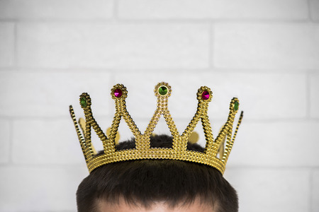The head of a man with a crown on it against a white brick wallの写真素材