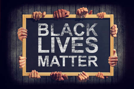 A lot of hand are holding a banner with text BLACK LIVES MATTER on dark background. Different people express one common opinion Black lives matter.の写真素材