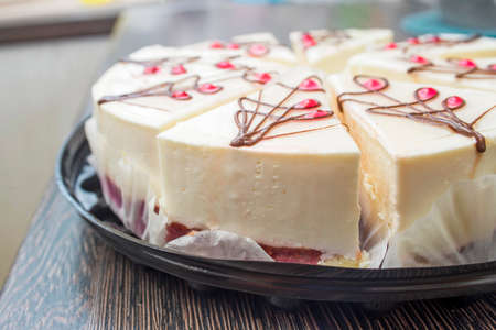 Cheesecake with raspberry jelly on black dish on a wooden table. Sliced cheesecake.の写真素材