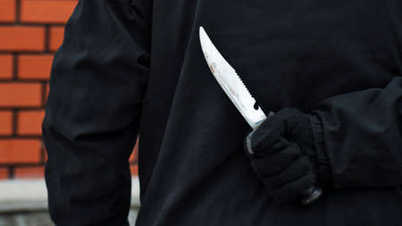 Man with the knife behind his back. Man holding sharp knife behind his back.の写真素材