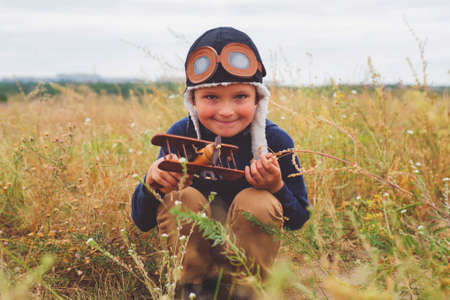Happy child playing with a toy wooden plane outdoors. Little boy with wooden plane.