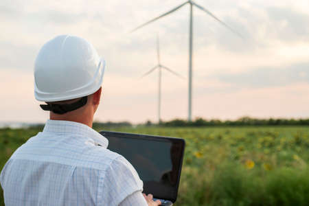 Engineer in a wind turbine. A man in a helmet with the tablet supervises the operation of the...