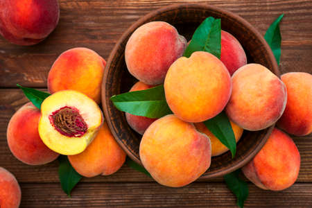 Ripe and tasty and juicy peaches lie on a plate on a wooden table. Large peaches on rustic wooden background, selective focus.の写真素材