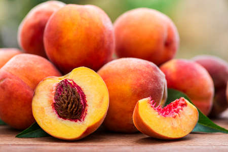 Fresh peaches on wooden table. Ripe peaches with leaves on a wooden board.の写真素材