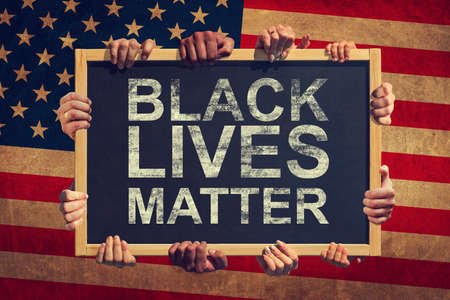 A lot of hand are holding a banner with text BLACK LIVES MATTER on background of American flag. Black lives matter.の写真素材