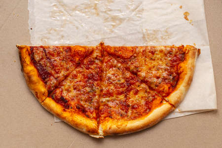 Piece of pizza in cardboard pizza box. Pizza box with leftowers. Top view.の写真素材