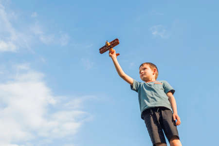 Little boy plays with a toy wooden plane. Child holds a toy wooden plane.の写真素材