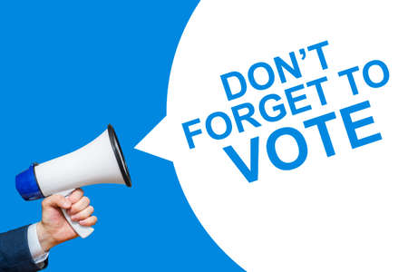 A hand is holding a megaphone with DON'T FORGET TO VOTE speech bubble. DON'T FORGET TO VOTE.の写真素材