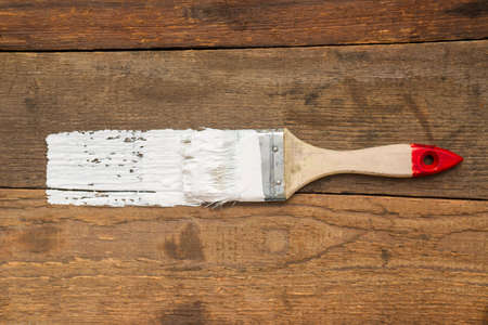 Brush with white paint on a wooden background. There is a place for advertising or inscription.の写真素材
