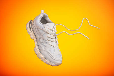 One sneaker is hanging in front of colorful background. One sneaker shoe on yellow background flies in air.の写真素材