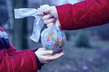 Hand of a little child reaching out to take a globe in plastic bag from an adult so he can take care of the earth for his future. Save the earth. World environmental day.の写真素材