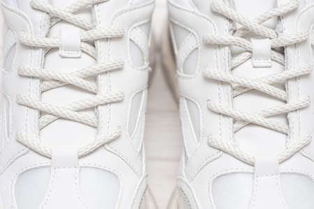 Part of a white sneakers with laces. A fragment of white shoes. A piece of sneaker. Fashionable sneakers.の写真素材