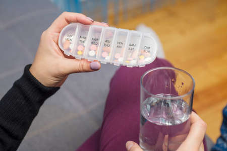 Woman taking medication. Woman holding a pills box and a glass of water. Healthcare concept with medicinesの写真素材