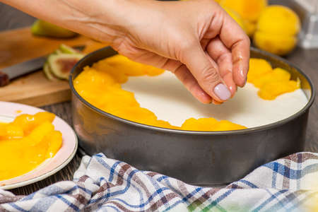 Cooking cheesecake. The cook decorates the cheesecake with sliced fruit. Woman decorates cheesecake.の写真素材