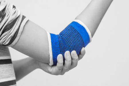 Elbow wrapped in elastic bandage, elbow pain. A child with a therapeutic elastic band on his elbowの写真素材
