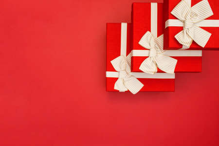 Red gift boxes on red background. Gift boxes tied with gold ribbon and bows on red background. Top...