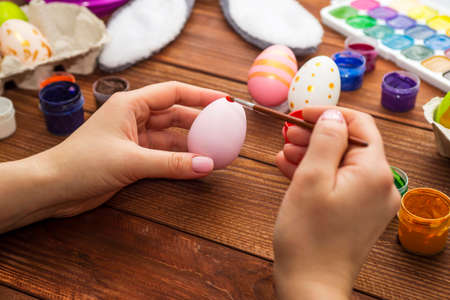 A woman with a tassel paints Easter eggs. Preparing decorations for Easter, creativity with children, traditional symbols. Preparing for Easter.の写真素材