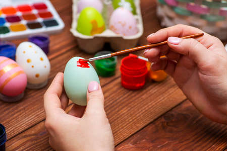 A woman with a tassel paints Easter eggs. Preparing decorations for Easter, creativity with children, traditional symbols. Preparing for Easter.の写真素材