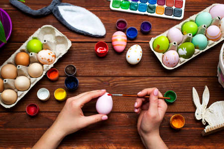 A woman with a tassel paints Easter eggs. Preparing decorations for Easter, creativity with children, traditional symbols. Preparing for Easter.の写真素材